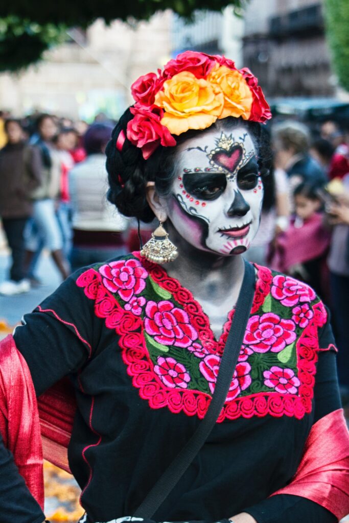 Woman wearing traditional Mexican clothing and skeleton face makeup for Day of the Dead.