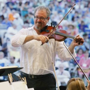 Greg Vitale plays violin with a large crowd behind him in the foreground.