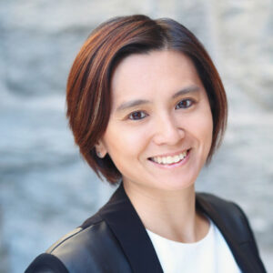 Katherine Chan is smiling and wearing a white shirt with a black blazer.