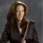 Headshot of Lisa Hennessy - she is smiling, looking off to the side, holding her flute.