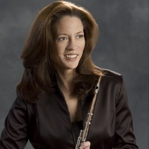 Lisa Hennessy is smiling and holding her flute. She is wearing a black shirt.