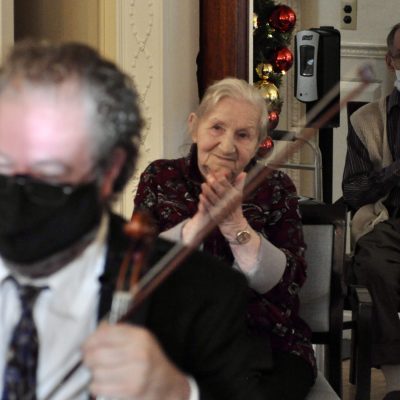 Resident of a facility for Music and Memory applauds as a member of Landmarks String Quartet plays.