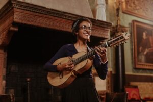 Fabiola Mendez holds her cuatro, smiling off to the side.