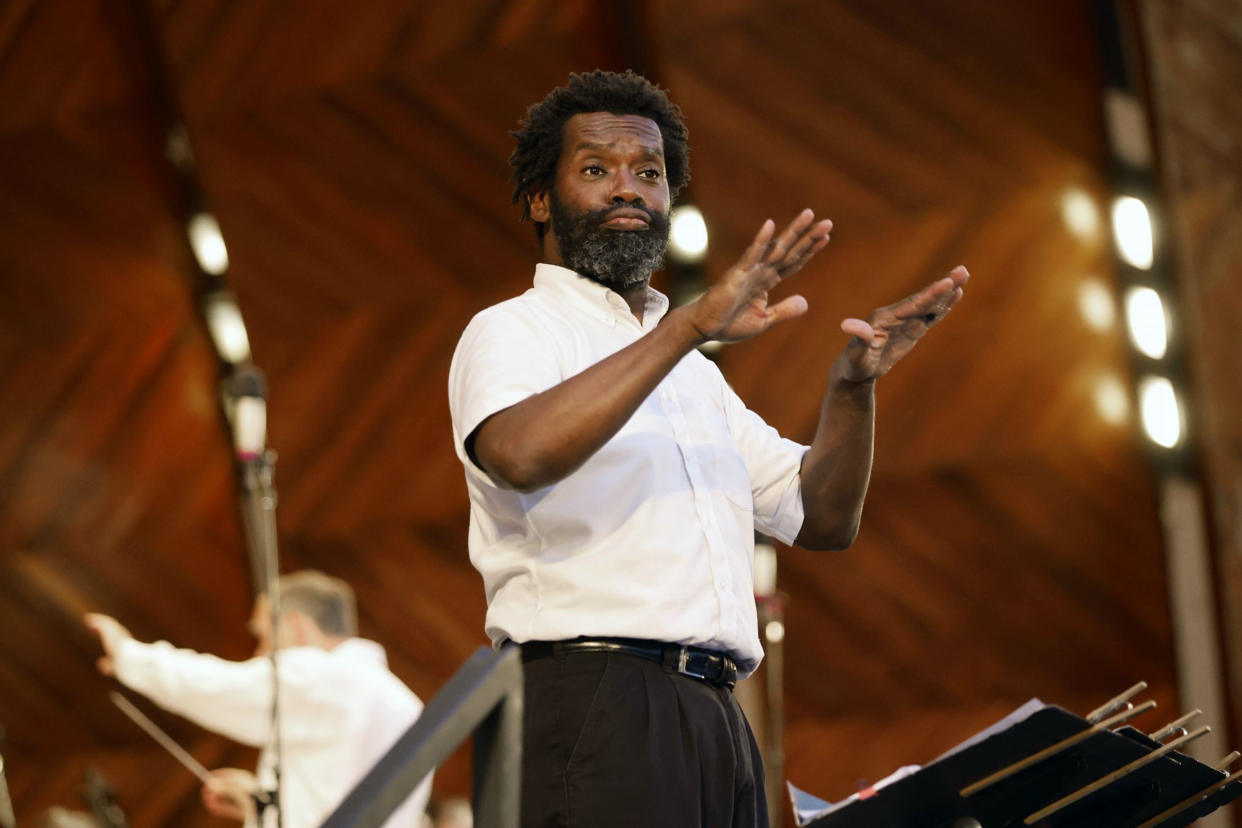 ASL Interpreter, Christopher Robinson is signing onstage at the Hatch Shell, with Music Director, Christopher Wilkins conducting behind him.