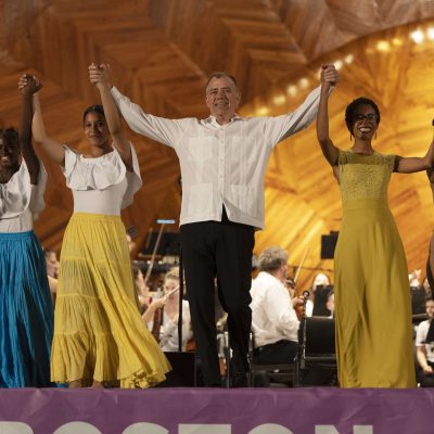Music Director Christopher Wilkins stands for a bow, with students from Hyde Square Task Force and Fabiola Mendez after a performance on the Hatch Shell.