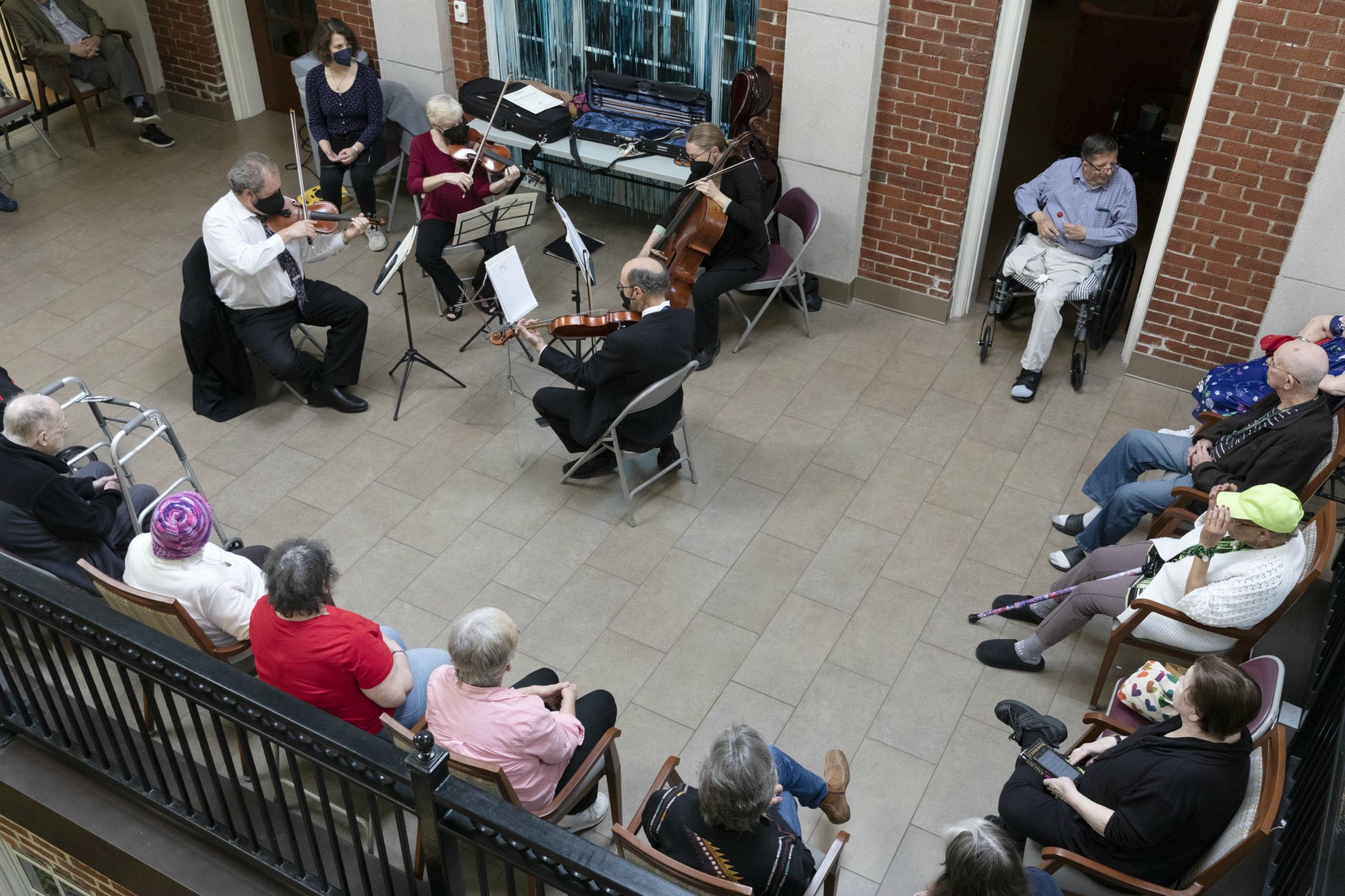 Residents at a nursing facility sit and watch Landmarks Orchestra's string quartet perform.