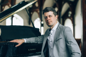 Headshot of Noah Horn sitting at the piano.